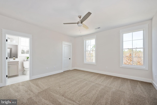 interior space with ceiling fan, multiple windows, and light carpet