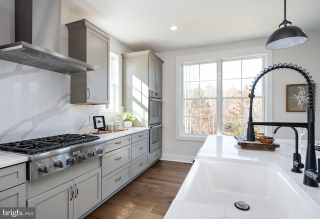 kitchen featuring sink, appliances with stainless steel finishes, wall chimney exhaust hood, dark hardwood / wood-style floors, and gray cabinets