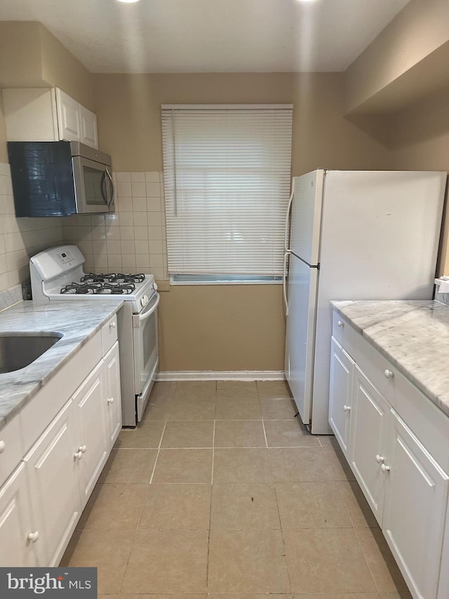 kitchen featuring white cabinets, light stone countertops, white appliances, and backsplash