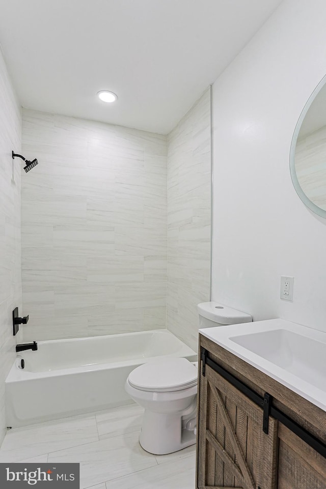 full bathroom featuring vanity, tiled shower / bath, and toilet