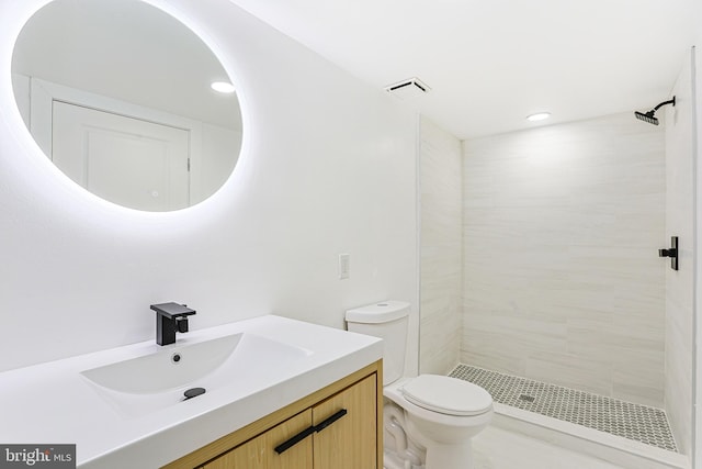 bathroom with toilet, vanity, and tiled shower