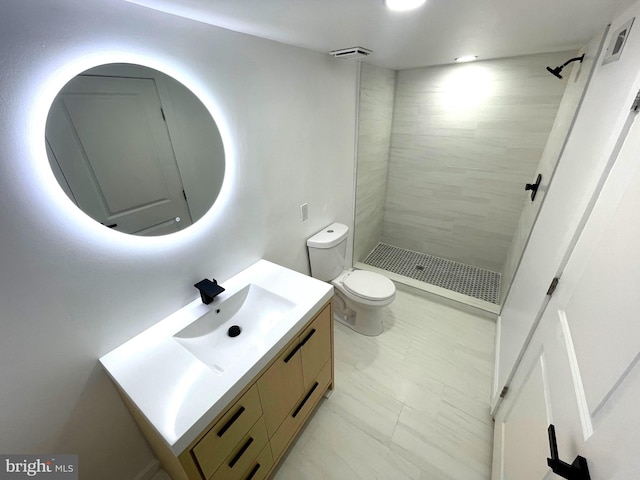 bathroom featuring vanity, tiled shower, and toilet