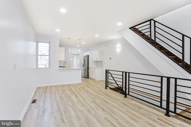 unfurnished living room with sink and light hardwood / wood-style floors