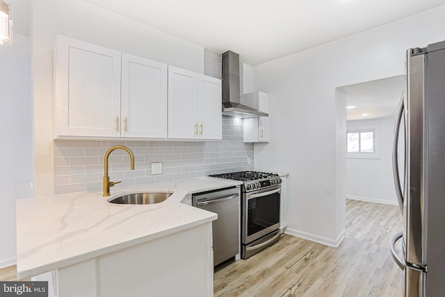 kitchen featuring wall chimney range hood, white cabinets, stainless steel appliances, and sink