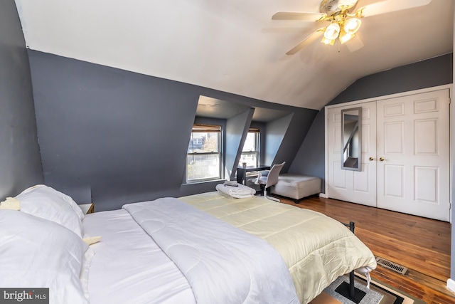 bedroom with a closet, ceiling fan, hardwood / wood-style flooring, and vaulted ceiling