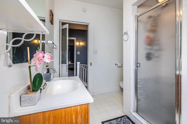 bathroom featuring vanity, a shower with shower door, toilet, and tile patterned floors