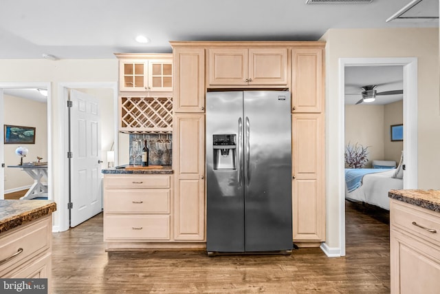 kitchen with stainless steel refrigerator with ice dispenser, light stone countertops, ceiling fan, and dark hardwood / wood-style flooring