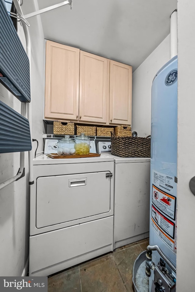 clothes washing area with cabinets, water heater, and washing machine and dryer