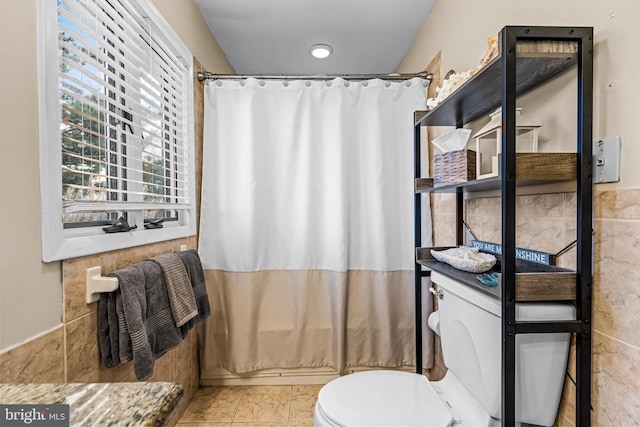 bathroom featuring vanity, toilet, tile patterned floors, and tile walls