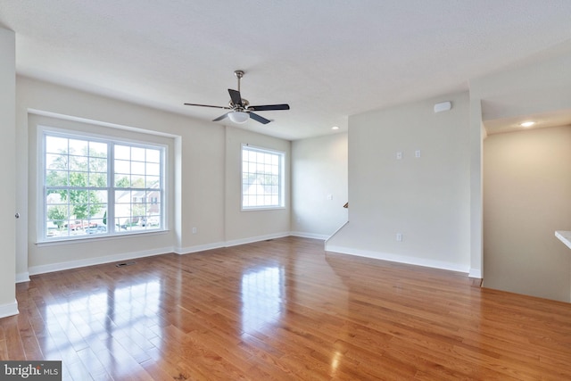 empty room with hardwood / wood-style flooring, plenty of natural light, and ceiling fan