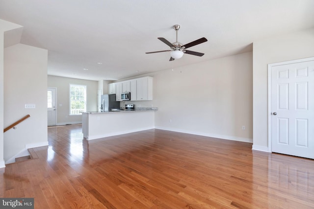 unfurnished living room with light wood-type flooring and ceiling fan