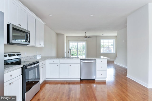 kitchen featuring light hardwood / wood-style floors, appliances with stainless steel finishes, kitchen peninsula, and white cabinets