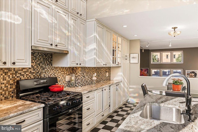 kitchen with black range with gas stovetop, tasteful backsplash, sink, and light stone counters