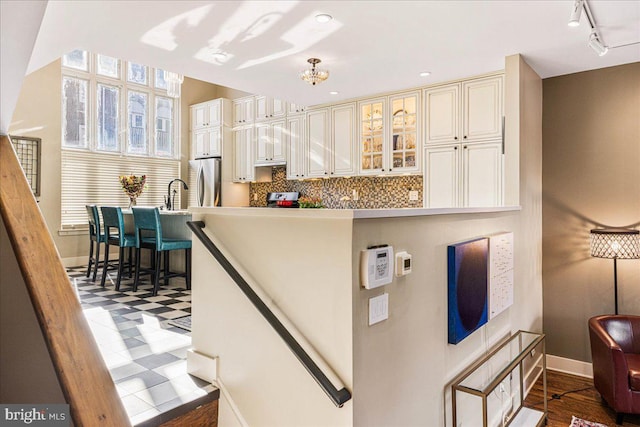 kitchen featuring dark wood-type flooring, backsplash, appliances with stainless steel finishes, and track lighting