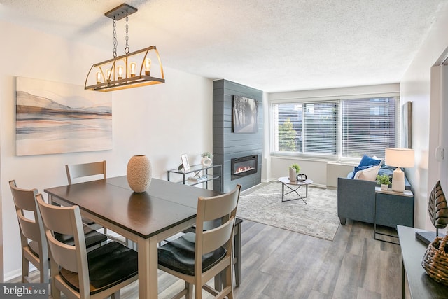 dining space with a fireplace, hardwood / wood-style floors, a textured ceiling, and a chandelier