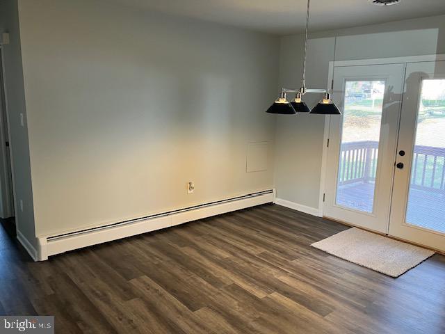 unfurnished dining area featuring french doors, a baseboard heating unit, and dark hardwood / wood-style floors