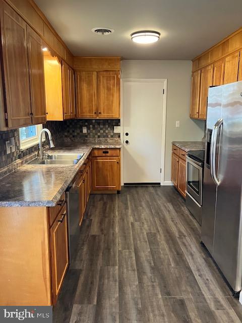 kitchen featuring dark wood-type flooring, tasteful backsplash, stainless steel appliances, and sink