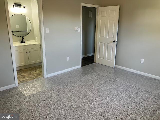 unfurnished bedroom with connected bathroom and sink