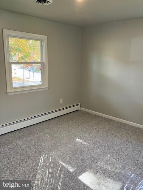 spare room with carpet floors and a baseboard radiator