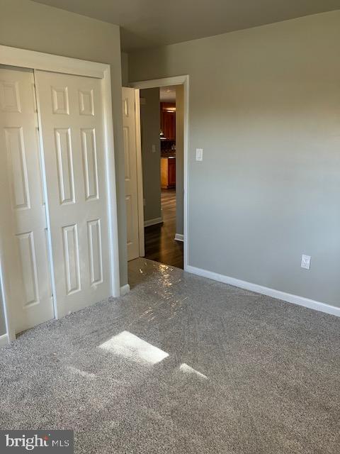 unfurnished bedroom with a closet and dark colored carpet