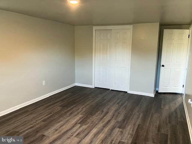 unfurnished bedroom featuring a closet and dark hardwood / wood-style flooring