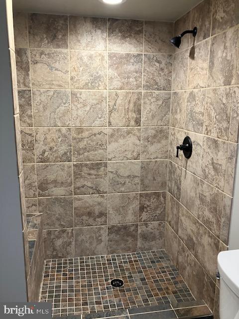 bathroom with toilet and tiled shower