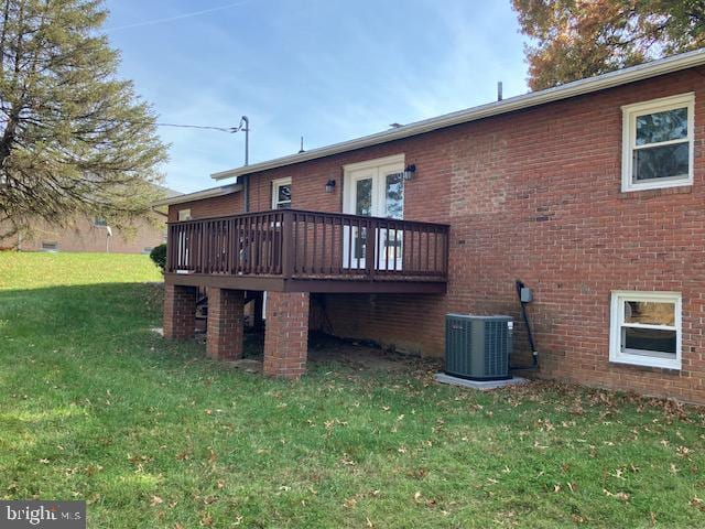 back of property with central AC, a wooden deck, and a lawn