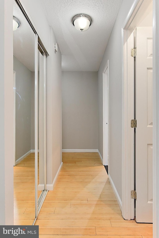 hall featuring light hardwood / wood-style floors and a textured ceiling