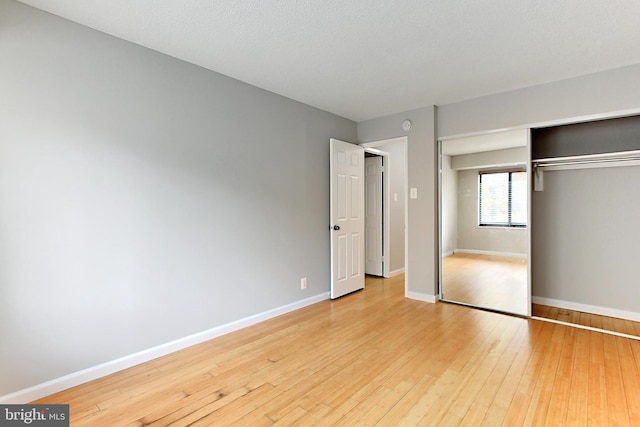 unfurnished bedroom with light wood-type flooring, a textured ceiling, and a closet