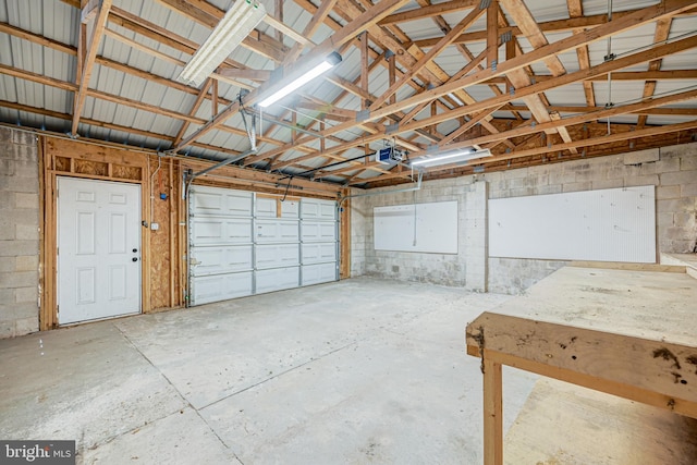 garage featuring concrete block wall and a garage door opener