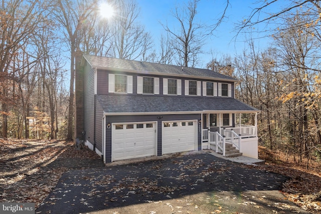 traditional-style house with asphalt driveway, a garage, a porch, a chimney, and a shingled roof