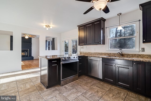 kitchen featuring pendant lighting, stainless steel appliances, a wood stove, and a healthy amount of sunlight