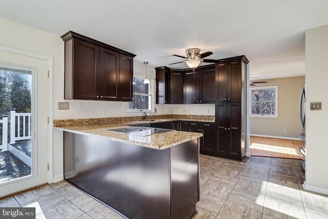 kitchen featuring kitchen peninsula, black electric stovetop, light wood-type flooring, dark brown cabinets, and hanging light fixtures