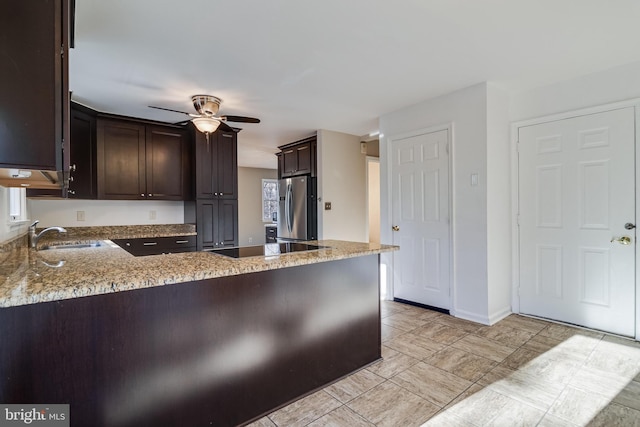 kitchen with kitchen peninsula, light stone countertops, ceiling fan, and stainless steel refrigerator with ice dispenser