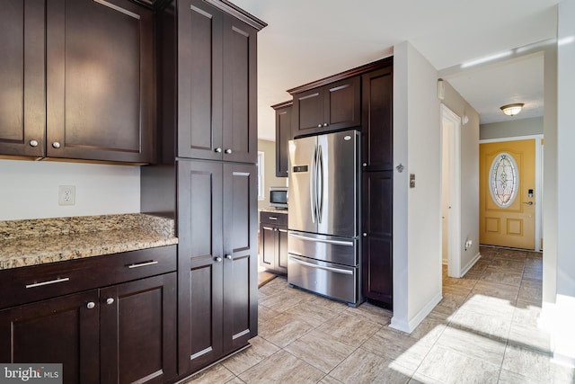 kitchen featuring dark brown cabinets, stainless steel appliances, and light stone counters