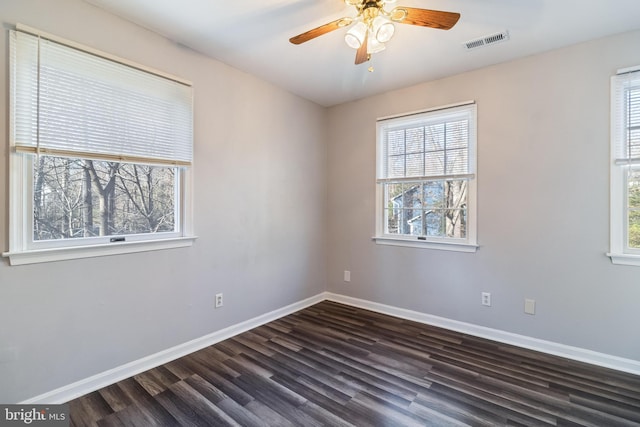 empty room with dark hardwood / wood-style floors, a wealth of natural light, and ceiling fan