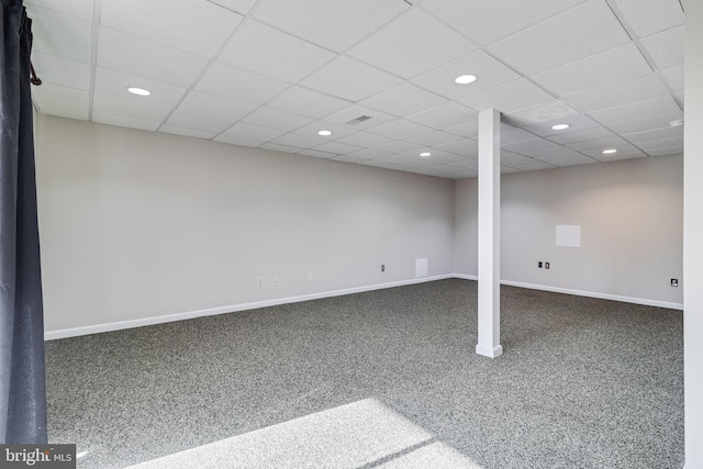 basement featuring dark colored carpet and a drop ceiling