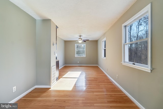 empty room featuring a wealth of natural light, light hardwood / wood-style flooring, and ceiling fan