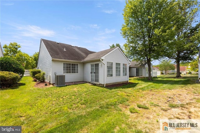 rear view of property featuring central AC and a lawn