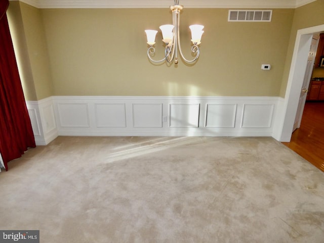 unfurnished room with light colored carpet, a notable chandelier, and ornamental molding