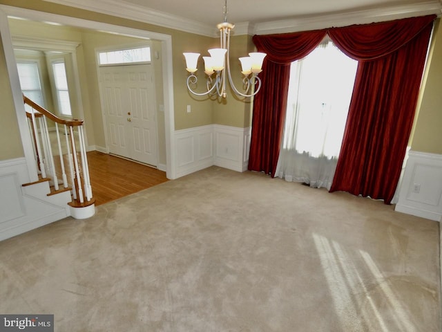 unfurnished dining area featuring a chandelier, ornamental molding, and carpet