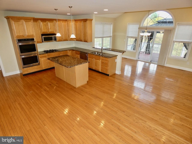 kitchen featuring stainless steel appliances, a kitchen island, pendant lighting, sink, and light hardwood / wood-style flooring