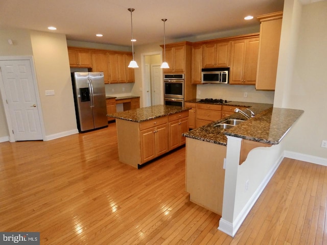 kitchen featuring sink, kitchen peninsula, appliances with stainless steel finishes, light hardwood / wood-style flooring, and pendant lighting