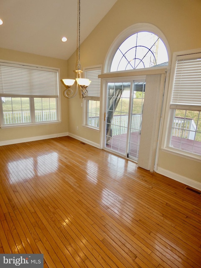 unfurnished dining area with a notable chandelier, a healthy amount of sunlight, and light hardwood / wood-style flooring