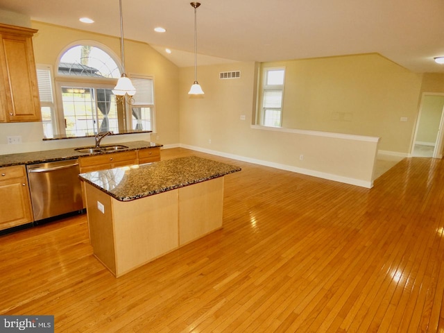 kitchen with light hardwood / wood-style floors, dark stone counters, vaulted ceiling, dishwasher, and a kitchen island