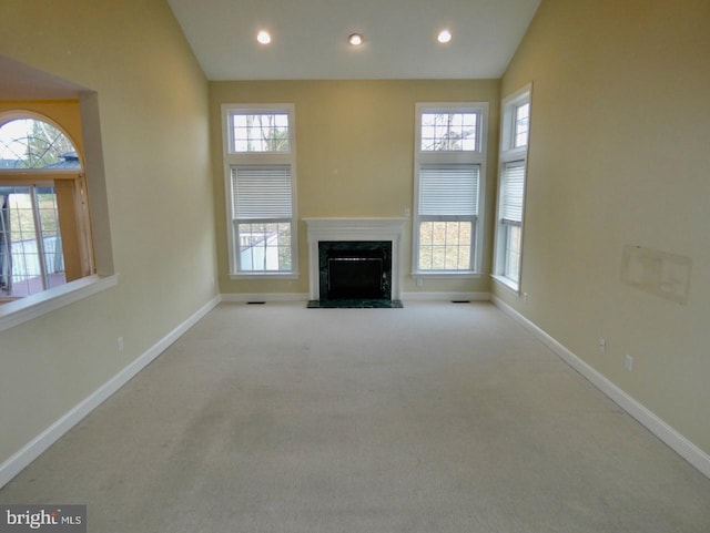 unfurnished living room featuring a fireplace, a wealth of natural light, light carpet, and high vaulted ceiling