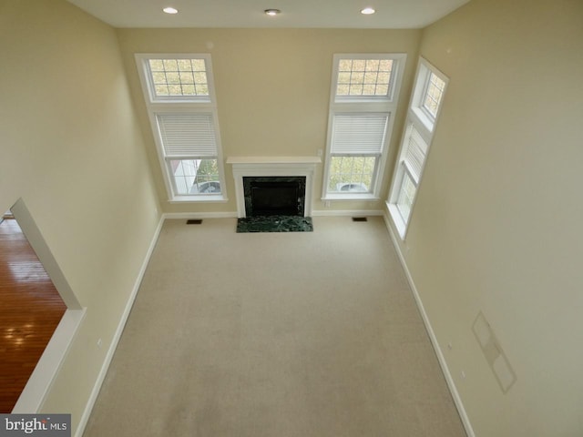 unfurnished living room with a wealth of natural light, light colored carpet, and a high ceiling