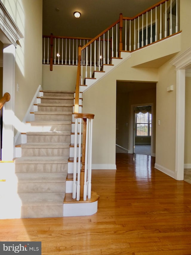 stairway featuring hardwood / wood-style floors and a towering ceiling