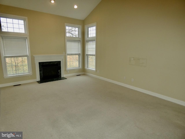 unfurnished living room featuring a high end fireplace, light carpet, and high vaulted ceiling