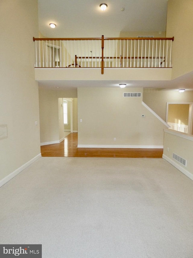 unfurnished living room with hardwood / wood-style floors and a towering ceiling